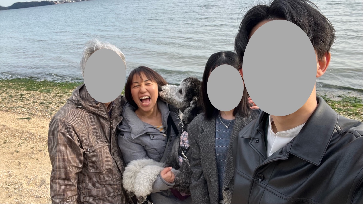 水辺で撮影した4人と大型犬の家族写真
