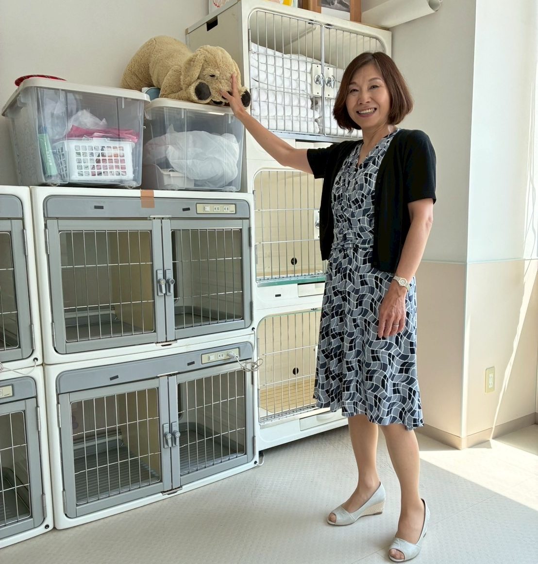 ペットケージの並ぶ部屋で微笑む理事長