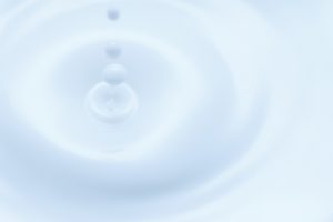 牛乳の表面に雫が触れて波紋が広がる様子