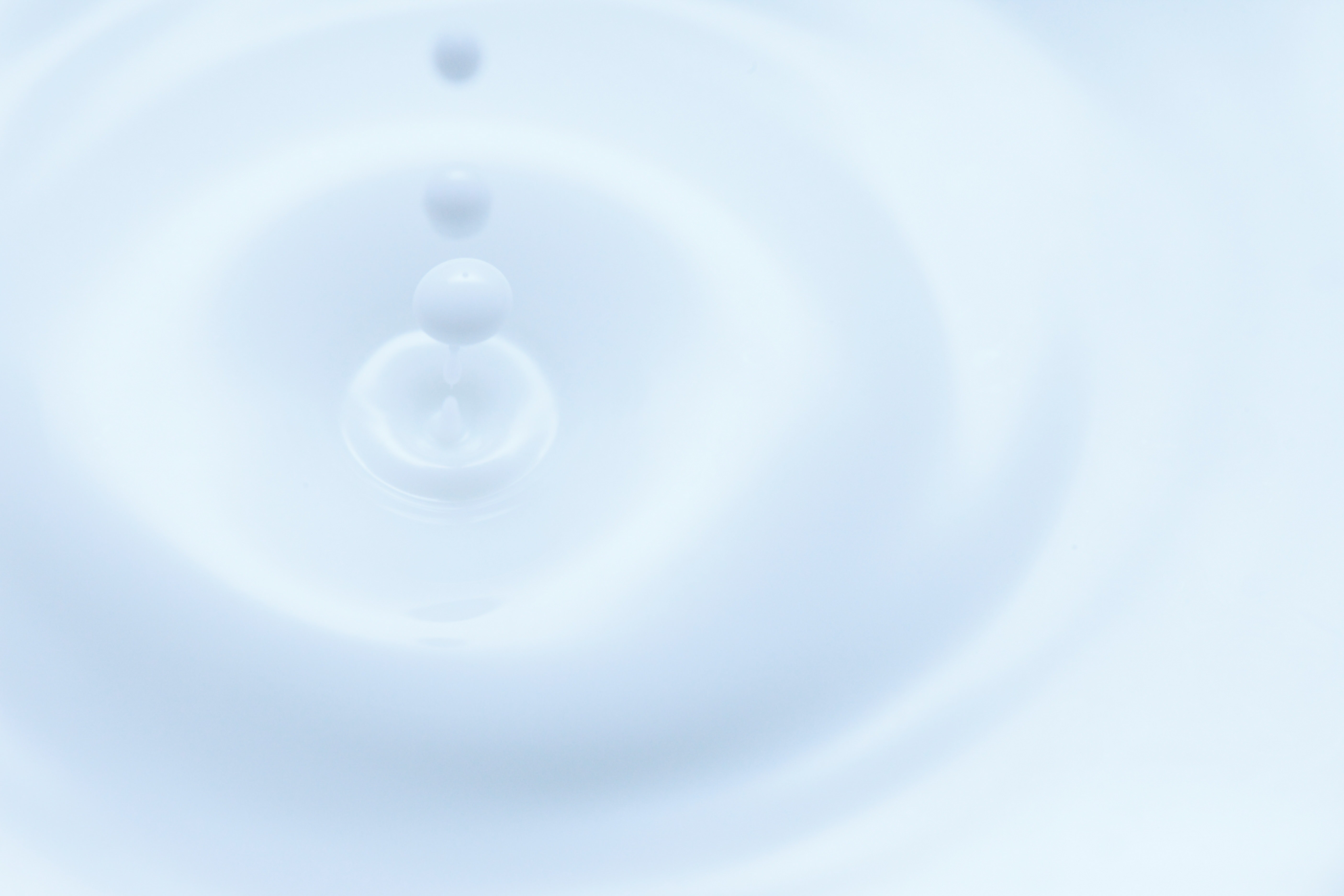 牛乳の表面に雫が触れて波紋が広がる様子